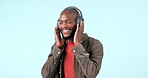 Headphones, dance or happy man streaming music to relax or freedom in studio on blue background. Smile, excited or African person listening to a radio song, sound or audio on an online subscription
