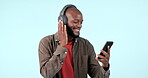 Headphones, smartphone or happy black man listening to music for freedom in studio on blue background. Smile, search or African person streaming a radio song, sound or audio on an online mobile app
