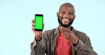 Pointing, green screen or happy black man with phone discount deal or sale on logo space. Advertising, smile or face of African person with mockup, news or mobile app promotion on blue background 