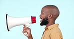 Speaker, megaphone and a man talking in studio for announcement or news on a blue background. Profile of a black person with a loudspeaker or bullhorn for voice, freedom of speech and broadcast