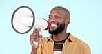 Megaphone, speaker and a man talking in studio for announcement or news on a blue background. Face of a happy black person with a loudspeaker or bullhorn for voice, freedom of speech and broadcast