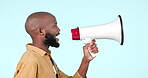 Talking, speaker and man with a megaphone in studio for announcement or news on blue background. Face or profile of black person with loudspeaker or bullhorn for voice, freedom of speech or broadcast