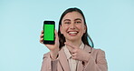 Phone, green screen and smile with a business woman pointing to mockup on a blue background in studio. Mobile, contact and a happy young employee showing tracking markers on a screen or display