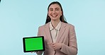Tablet, green screen and a happy business woman pointing to mockup on a blue background in studio. Technology, website and smile with a young employee showing tracking markers on a screen or display