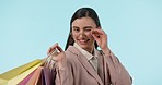 Face, glasses and woman wink with shopping bag in studio isolated on a blue background. Fashion portrait, happy customer and gifts on discount, sales and purchase at boutique, mall and retail store.