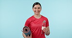 Water bottle, exercise mat and a woman in studio for a workout, health and wellness. Portrait of happy young female person on a blue background for fitness, hydration and training workout with space