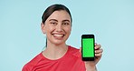 Green screen, phone and face of happy woman in studio with space for fitness, blog or sign up on blue background. Smartphone, display and portrait of female athlete show menu, application or process