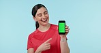 Green screen, hand pointing and woman face with phone in studio for fitness, app or sign up blue background. Smartphone, space and portrait of lady personal trainer show application, menu or process