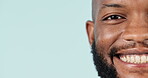 Half face, smile and mockup with a black man closeup in studio on a blue background for marketing. Portrait, space and a happy young person looking confident on an advertising backdrop for a logo