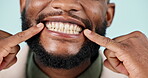 Mouth, teeth and closeup smile of man in studio isolated on a blue background. Happy face, pointing at lips and dental hygiene in tooth whitening, oral care and healthy gums for wellness at dentist