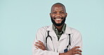 Face, happy black man and doctor with arms crossed in studio isolated on a blue background mockup space. Portrait, smile and confident medical professional, surgeon and healthcare worker in Nigeria.