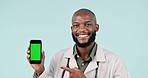 Black man, doctor and pointing to phone green screen, mockup or advertising against a studio background. Portrait of happy African male person show mobile smartphone display with tracking markers