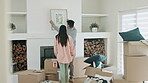 Art, decoration and couple together in new home or moving in with real estate property. Behind a man and woman hanging a frame in first house or living room with mortgage, boxes and interior design 