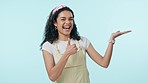 Woman, excited and pointing at news with thumbs up, information and agreement isolated on blue background. Announcement, brand ambassador and direction, opportunity and like with portrait in studio