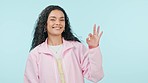 Ok, woman and face in studio with smile to vote for good review, yes emoji and laugh on blue background. Portrait, happy model and show perfect sign of success, agreement and icon to support feedback