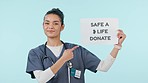 Donate, sign and woman face of nurse pointing to poster for blood, organ of healthcare donation in studio. Help, charity work and portrait with blue background and hospital billboard for advertising