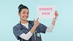 Donate, pointing and woman face of nurse with poster for blood, organ of healthcare donation in studio. Help, charity work and portrait with clinic and hospital advertising with blue background