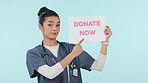 Studio, woman or doctor with sign to donate now or healthcare isolated on blue background. Face, help or medical worker pointing to poster, blood drop words or announcement text on board for info 