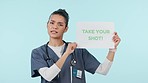 Board, woman or doctor with sign for flu shot or healthcare isolated on blue background. Face, help or medical worker pointing to poster, blood drop words or announcement text in studio for info 