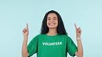 Woman, volunteer face and pointing up with yes to show advertising and NGO charity info. Blue background, studio and yes of mock up space for volunteering, nonprofit and community service opportunity