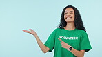 Woman, face and hand show volunteer advertising and NGO charity information. Blue background, studio and portrait with mock up space for volunteering, nonprofit and community service opportunity