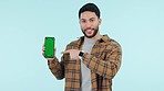 Face of man, show or green screen on a phone for social media advertising or online branding. Blue background, talking or person pointing to explain mobile app chroma key or mockup space in studio 