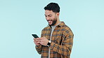 Happy man, phone and typing for social media, college communication and funny internet meme on blue background. Young person or student reading on mobile app for chat, news and laughing in studio
