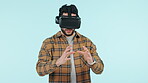 Virtual reality, metaverse and goggles with a man using technology in studio on a blue background. Future, software and 3D gaming with a young person playing esports in cyberspace using an AR app