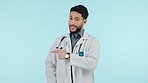 Medical doctor, pointing finger and a man in studio for announcement, advertising or review. Happy healthcare worker and hand gesture on blue background for direction, presentation or feedback banner