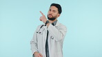 Medical doctor, pointing and a serious man in studio for announcement, advertising or bad review. Arab healthcare worker hand gesture on blue background for no, choice or negative feedback banner