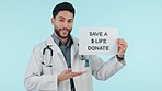 Donate, poster and man doctor with medical request as professional volunteer isolated in a studio blue background. Pointing, placard and healthcare employee ask for help in charity with sign