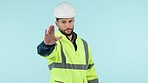 Face, man and engineer with stop, rejection and safety regulations on a blue studio background. Portrait, person and construction worker with hand gesture, warning and forbidden with deny or hard hat