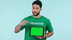 Man, volunteering and tablet green screen of eco friendly website, presentation or donation information in studio. Face, NGO person and digital mockup, pointing or tracking marker on blue background