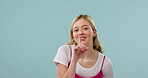 Woman, finger to lips for secret and face with confidential news, privacy and silence on blue background. Portrait, quiet gesture and smile, mockup space with gossip, whisper and no noise in studio