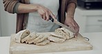 Bread, knife and hands of person in kitchen, bakery or restaurant for meal prep, dinner or breakfast. Cafe, startup and closeup of cutting slice of homemade loaf on wooden board for ingredients