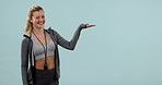 Fitness, smile and woman pointing at palm in studio isolated on a blue background. Portrait, hands advertising and marketing workout of coach or sports promotion of personal trainer on mockup space.