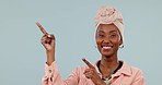 African woman, portrait and pointing in studio with announcement, advertising and smile. Face of black female person with a turban and hand gesture on a blue background for presentation and promotion