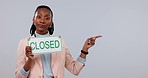 Black woman, closed sign and pointing of small business owner at mockup space in studio isolated on a white background. Portrait, entrepreneur and person closing for bankruptcy, crisis or advertising