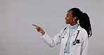 Happy black woman, doctor and pointing to list, options or advertising on mockup against a studio background. Portrait of African female person or healthcare worker show choice, steps or information