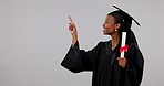 Happy black woman, graduation and pointing with certificate in advertising against a studio background. Portrait of African female person, student or graduate showing list, qualifications or diploma