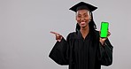 Black woman, graduation and phone with green screen pointing to mockup space in advertising against a studio background. Portrait of African female person or student graduate show smartphone display