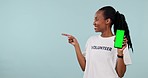 Woman, volunteering and phone green screen, presentation mockup and support, join us or advertising in studio. Face of young african student on mobile app, pointing to information and blue background