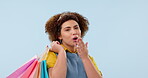 Retail, shopping and a woman blowing a kiss on a blue background in studio as a store customer. Portrait, smile and a happy young shopper looking for a luxury fashion sale, deal or commerce discount