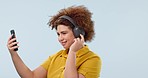 Phone, music headphones and happy woman in wind, streaming media and listen to audio online. Dancing, radio and person moving to sound for freedom isolated on a blue background mockup space in studio