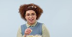 Glasses, funny and woman eating popcorn at cinema in studio isolated on a blue background mockup space. Food, wow and laughing person watch comedy movie in theater, streaming film and television show