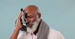 Senior, tired black man and sweating from fitness, exercise and workout with towel wipe in studio. Athlete break and training of a coach with wellness and healthcare from sport with blue background