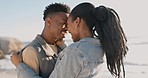 Black couple, hug and beach with love, bonding and care together by the sea with smile. Happy, freedom and vacation with young people relax with embrace by ocean on adventure with travel and peace