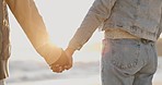 Couple, holding hands and beach with love, bonding and care together by the sea. Back, freedom and vacation with young people relax with sunset by ocean on adventure with travel and marriage