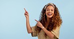 Face, pointing and woman with a smile, promotion and announcement on a blue studio background. Portrait, person and model with hand gesture, presenting or decision with opportunity, excited or choice