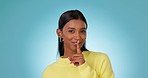 Secret, face and woman with finger on lips in studio for sign of privacy, confidential mystery or surprise on blue background. Happy portrait, indian model and quiet emoji for gossip, news or whisper